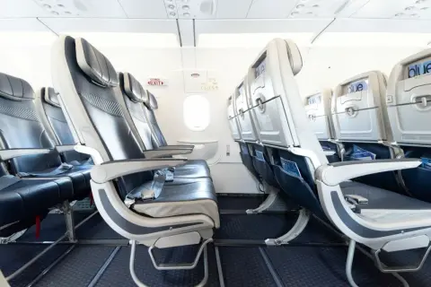 Leere Sitze in einem Flugzeug von Freebird Airlines. Blaue und graue Polster, Bildschirme an den Rückenlehnen.