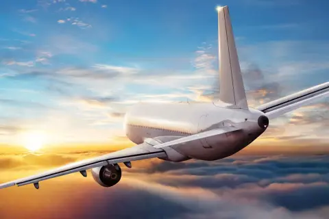 Ein Flugzeug fliegt über Wolken bei Sonnenuntergang. Die Frage, wie sicher ist fliegen aktuell, wird durch diese friedliche Szene beantwortet.