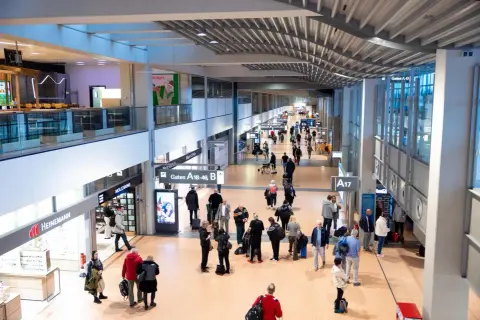 Menschen im Hamburger Flughafen, einige eilen zu ihren Gates, andere suchen nach Möglichkeiten, Geld zu wechseln.