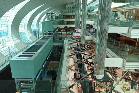 Der Flughafen Dubai innen: ein modernes Einkaufsparadies mit Glas und Stahl. Helle Gänge, Geschäfte und Palmen laden zum Verweilen ein.