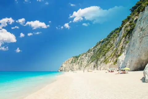 Traumhafter **Griechenland Sandstrand** mit türkisblauem Meer, weißen Klippen und einigen Sonnenanbetern.