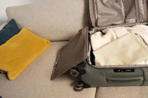 Koffer packen für den Urlaub. Kleidung wird sorgfältig in den Koffer gelegt, bereit für die Reise.