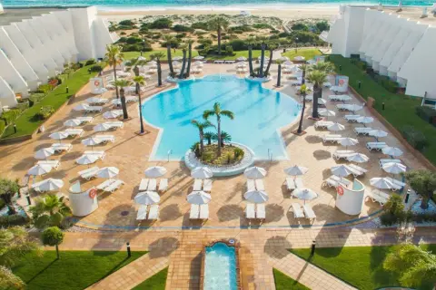 Traumhafter Poolbereich mit Liegen und Sonnenschirmen am IBEROSTAR Royal Andalus. Der Strand und das Meer sind im Hintergrund zu sehen.