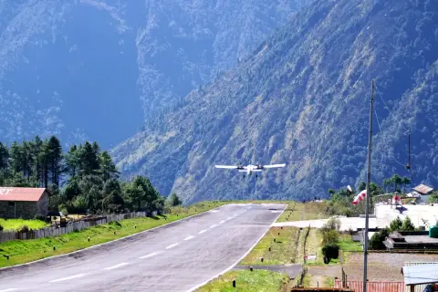 Flugzeug landet auf dem Lukla Airport, umgeben von steilen, bewaldeten Bergen.