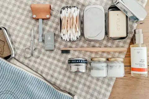 Kosmetik urlaub liste: Rasierer, Seife, Wattestäbchen, Zahnbürste, Cremetiegel und Rosenöl für die Reiseapotheke.