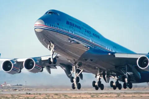Ein Jumbo Jet 747 hebt ab, seine vier Triebwerke dröhnen.