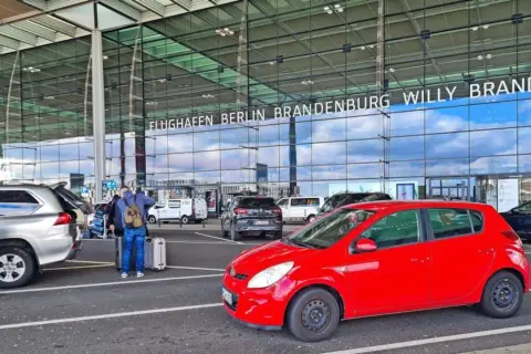 Am Flughafen Berlin Brandenburg Willy Brandt parken Autos. Die Kosten für das Parken sind hier nicht ersichtlich, aber die An- und Abfahrt ist gut organisiert.