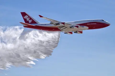 Eine Boeing 747, die als Global Supertanker zur Brandbekämpfung eingesetzt wird, sprüht Wasser. Sie fliegt schnell, um Brände zu löschen.