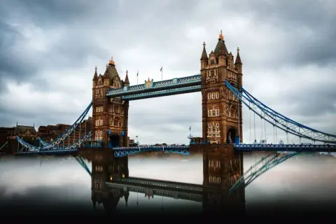 Der Tower Bridge in London, ein Wahrzeichen für jeden England Urlaub, spiegelt sich im Wasser.