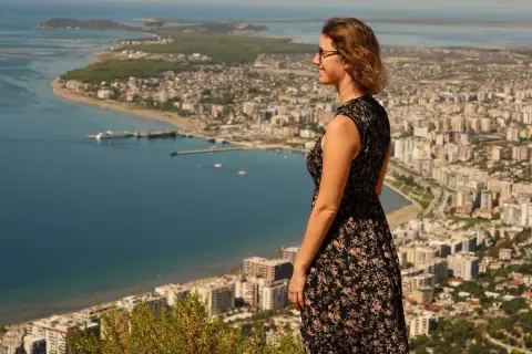 Frau genießt den Ausblick auf eine Stadt am Meer während ihres Urlaubs in Albanien.