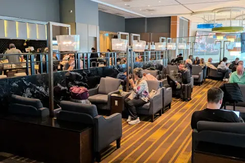Gemütliche Sitzecken und ein Buffetbereich in einer **priority lounge**. Reisende entspannen sich, arbeiten oder essen.