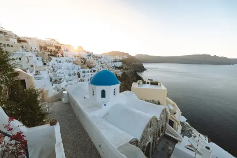 Ein malerischer Blick auf Oia, Santorini, mit seinen weiß getünchten Häusern und der ikonischen blauen Kuppelkirche. Perfekt für einen Santorini Urlaub.