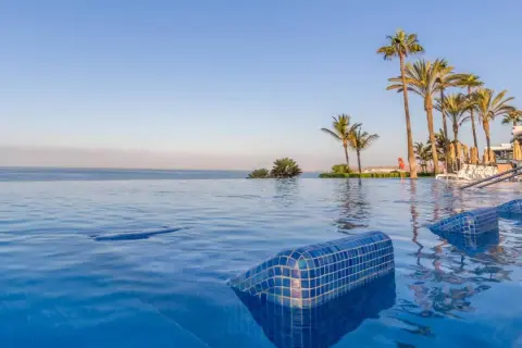 Infinity-Pool mit Blick auf das Meer und Palmen am Riu Palace Meloneras. Entspannung pur im blauen Wasser.