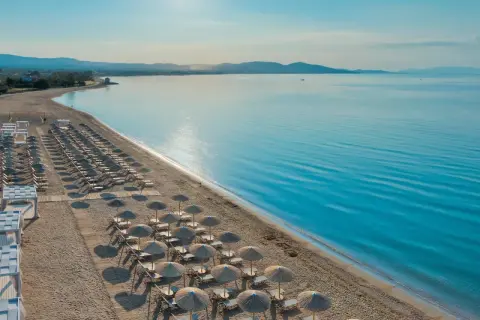 Ein traumhafter Strand mit vielen Liegen und Sonnenschirmen, bereit für Gäste des TUI Blue Lagoon Princess. Das Meer glitzert in der Sonne.