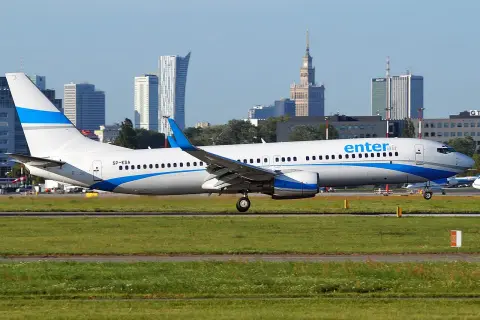 Ein Enter Air Flugzeug rollt auf dem Rollfeld, die Skyline von Warschau im Hintergrund.
