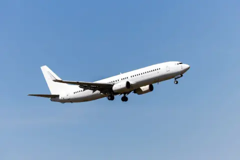 Ein weißes Flugzeug steigt in den blauen Himmel auf. Die Frage, wie hoch fliegt ein Flugzeug, bleibt offen, aber dieser Anblick lässt die Fantasie fliegen.