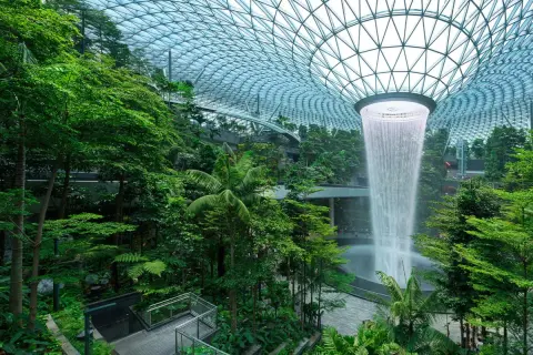 Imposanter Wasserfall im tropischen Garten des Flughafens Singapur. Die beeindruckende Architektur und üppige Vegetation lassen die **Singapur Flughafen Kosten** vergessen.