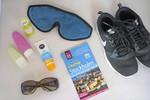 Packliste Wochenende: Sonnencreme, Schlafmaske, Sonnenbrille, Reiseführer Stockholm und Turnschuhe für Stadterkundungen.