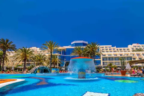 Einladender Poolbereich mit Wasserrutsche und Palmen vor dem Costa Calma Palace Hotel.