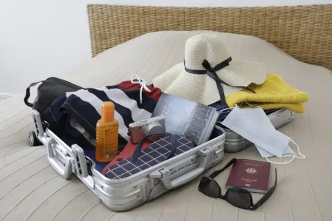 Packliste Istanbul: Koffer mit Badesachen, Sonnencreme, Kamera, Hut, Buch, Masken, Reisepass und Sonnenbrille.