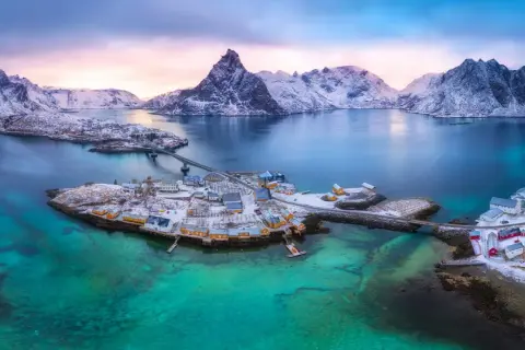 Winterliche Lofoten: Ein Traum für jeden Skandinavien Urlaub. Schneebedeckte Berge, türkisfarbenes Wasser und malerische Fischerdörfer.
