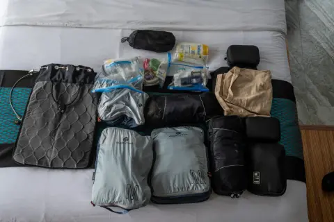 Packliste Thailand: Gepäckstücke, Kulturbeutel und Kleidung sind ordentlich auf dem Bett ausgebreitet.