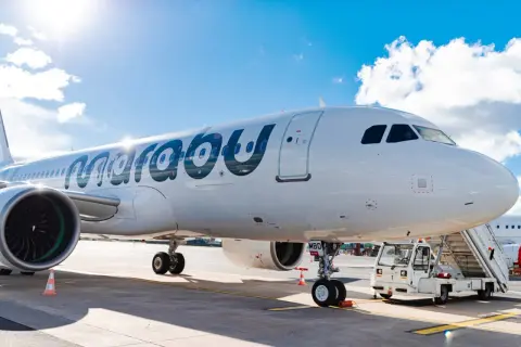Ein weißes Flugzeug der Marabu Airlines steht am Flughafen. Die Sonne scheint auf den Rumpf, und eine Treppe ist am Eingang angebracht.