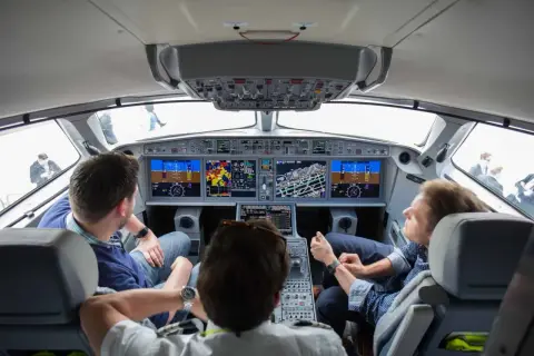Einblick ins Cockpit: Drei Männer blicken auf die Instrumente, während sie im Flugzeug mitfliegen.