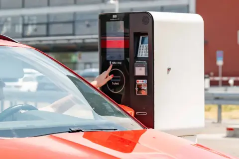 Frau am Parkscheinautomaten am Flughafen Memmingen. Hier kann man kostenlos parken, wenn man den richtigen Tarif wählt.