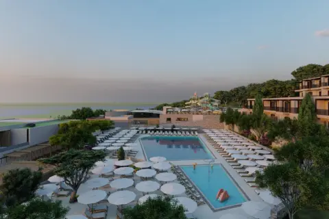 Ein luxuriöses Resort am Elios Hill Kreta mit Pools, Wasserrutschen und Blick aufs Meer. Sonnenschirme und Liegen laden zum Entspannen ein.