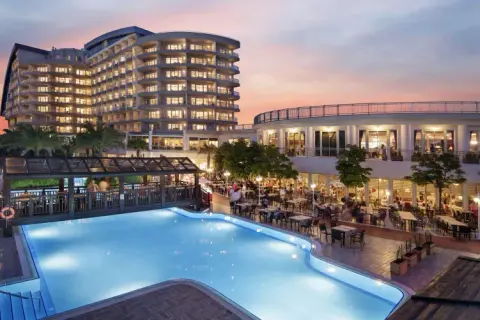 Abendstimmung am Pool des Liberty Lara Hotels. Gäste genießen das Abendessen im Freien unter dem farbenprächtigen Himmel.