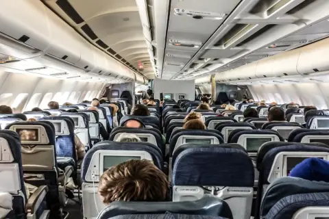Blick in die Kabine eines Flugzeugs mit vielen Reihen von Langstreckenflug Sitzen, einige mit Bildschirmen.
