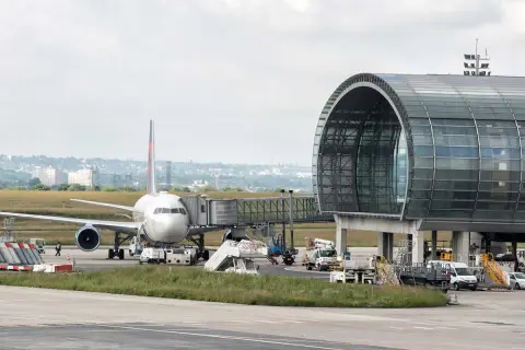 Flugzeug am Gate mit modernem Terminalgebäude. Die Frage "paris welcher flughafen am besten" wird hier nicht beantwortet, aber die Szene zeigt einen belebten Flughafen.