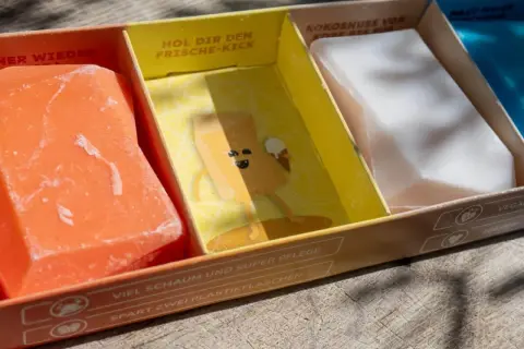 Erste Eindrücke von Duschbrocken: Ein orangefarbener, ein gelber mit Comic und ein weißer festes Shampoo. Umweltfreundlich & pflegend.