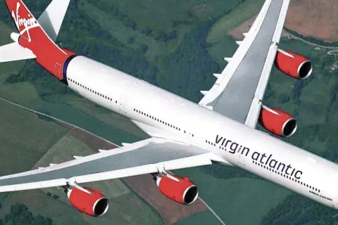 Ein Airbus A340-600 der Virgin Atlantic Flotte fliegt über grüne Landschaften.