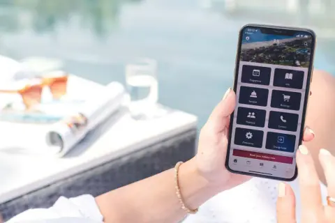Frau nutzt Handy-App, um eine TUI Reise zu stornieren. Auf dem Bildschirm sind Optionen wie "Bookings" und "Change hotel" sichtbar.