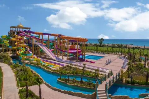 Ein riesiger Wasserpark mit bunten Rutschen, einem Lazy River und Pools. Das Meer im Hintergrund. Ein delphin be grand Urlaubstraum.