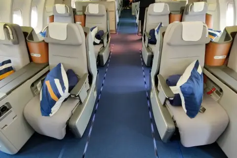 Lufthansa Business Class Sitze mit blauen Kissen und Decken. Ein Blick in den Gang, der Hoffnung auf einen Standby-Ticket-Lufthansa-Traumflug macht.