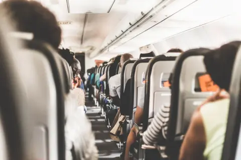 Blick in die enge Flugzeugkabine, wo die Sitze dicht an dicht stehen. Ein Gefühl von Platzangst im Flugzeug kann aufkommen, wenn man die vielen Passagiere sieht.