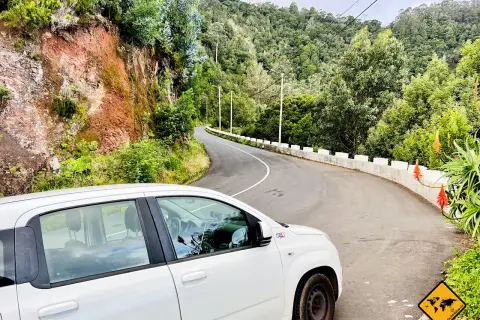 Ein weißer Mietwagen auf einer kurvigen Straße auf Madeira. Braucht man auf Madeira einen Mietwagen? Ja, um diese Aussicht zu genießen!