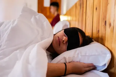 Frau schläft mit Schlafmaske, um Jetlag zu bekämpfen. Die Richtung des Jetlags ist egal, Hauptsache Schlaf.