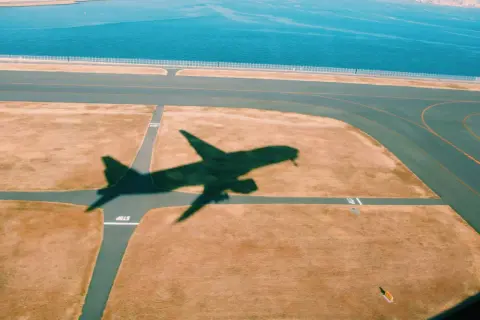 Schatten eines Flugzeugs auf dem Rollfeld. Gute tipps langstreckenflug: entspannt bleiben, Wasser trinken, bewegen.