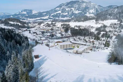 Winteridylle am Robinson Fieberbrunn: Hotelanlage mit Skilift und verschneiten Bergen im Hintergrund.