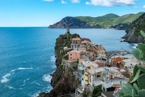 Bunte Häuser kleben an steilen Klippen am Meer. Ein perfekter Urlaub in Italien, mit Blick auf das azurblaue Meer und die Berge.