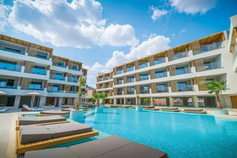 Entspannter Urlaub im Akasha Beach Hotel & Spa: Moderne Architektur, ein einladender Pool und Liegen unter blauem Himmel.
