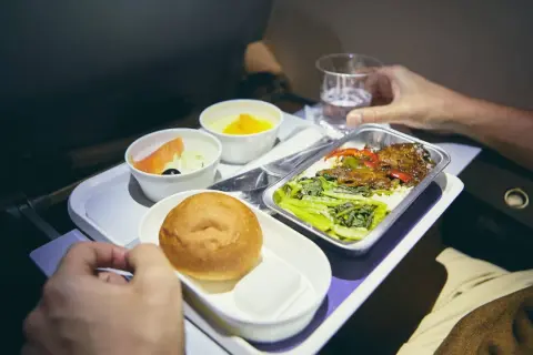 Flugzeugessen: Ab wann gibt es Essen? Ein Tablett mit Lachs, Brötchen, Dessert und Hauptgericht.