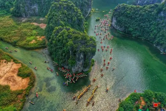 Boote auf einem grünen Fluss in Ninh Binh, umgeben von üppigen, felsigen Inseln.
