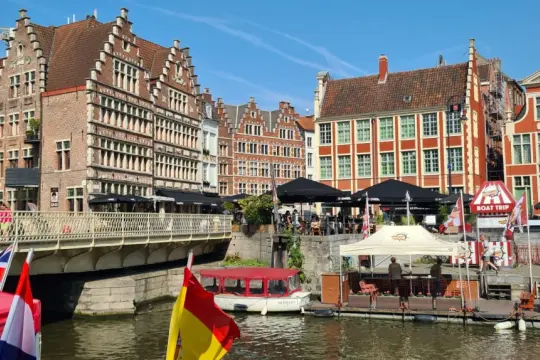 Historische Giebelhäuser säumen einen Kanal in Gent, Belgien. Boote und Terrassen laden zum Verweilen ein.