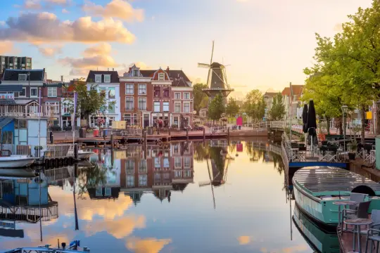 Ein malerischer Kanal in Leiden, Holland, mit traditionellen Häusern, einem Windrad und reflektierenden Wolken im Wasser.