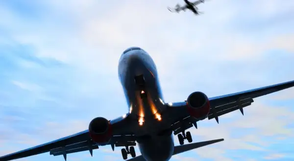 Ein landendes Flugzeug mit ausgefahrenem Fahrwerk im Gegenlicht, ein weiteres Flugzeug fliegt darüber.